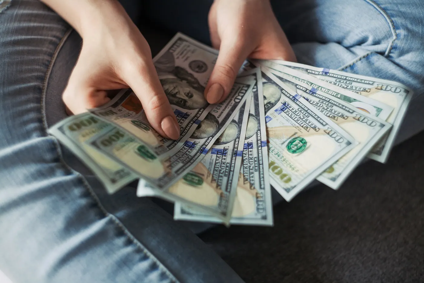 Hands holding a fan of US hundred-dollar bills